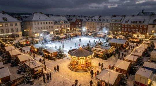 Vue nocturne d'un village de Noël éphémère avec patinoire illuminée, carrousel vintage et chalets en bois décorés